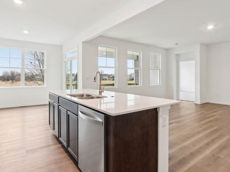 Isla de cocina con cuarzo y fregadero frente a las ventanas de la sala (foto del constructor)